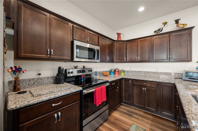 kitchen featuring stainless steel appliances, dark brown cabinets, light stone counters, and wood finished floors