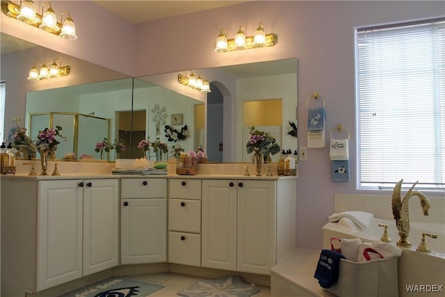 full bathroom featuring a sink, double vanity, a shower stall, and tile patterned floors