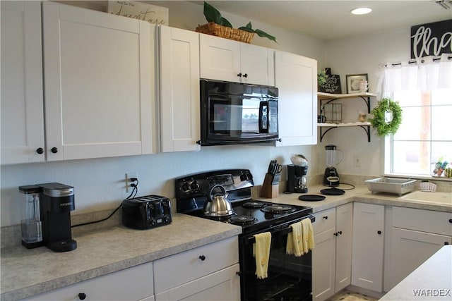 kitchen with black appliances, white cabinetry, light countertops, and a sink