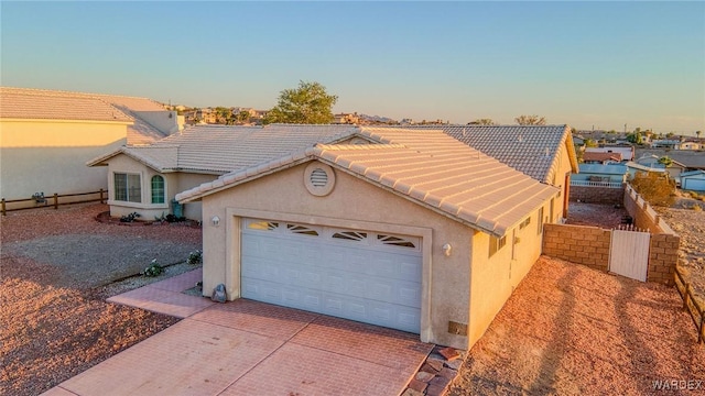 view of front of home with stucco siding, fence, decorative driveway, and a tiled roof