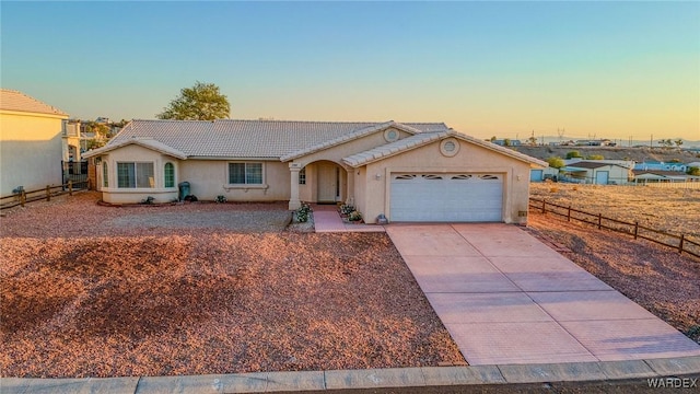 ranch-style house with a garage, fence, driveway, a tiled roof, and stucco siding