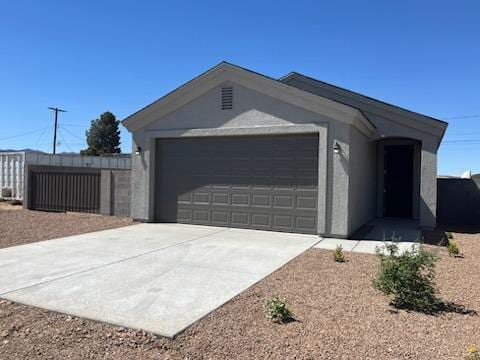 3515 E Lum Ave, Kingman, AZ 86409 - view of front of home featuring stucco siding, concrete driveway, a garage, and fence