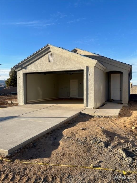 view of front of house featuring driveway, an attached garage, and stucco siding