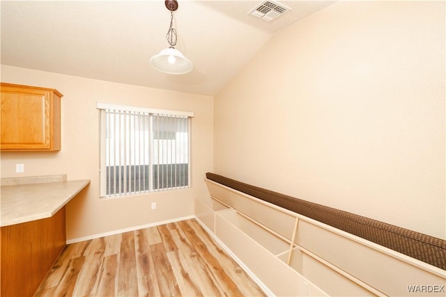 unfurnished dining area featuring lofted ceiling, baseboards, visible vents, and light wood-type flooring