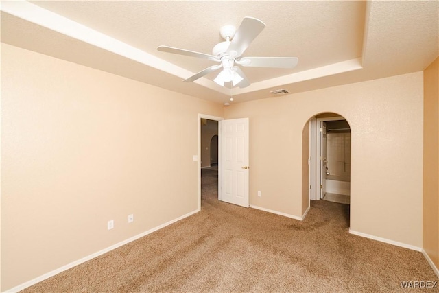 interior space with visible vents, a ceiling fan, arched walkways, carpet, and baseboards