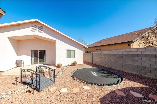 rear view of property featuring a patio area, fence, and stucco siding