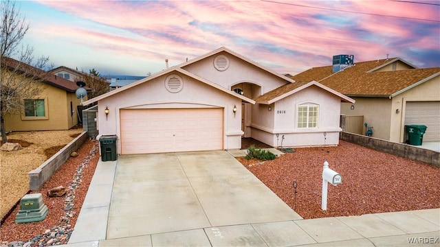 ranch-style home featuring fence, concrete driveway, central AC unit, stucco siding, and an attached garage