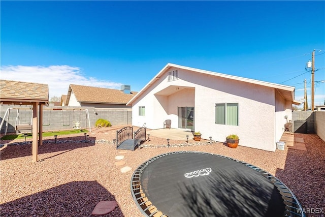 rear view of house featuring stucco siding, a patio, and a fenced backyard