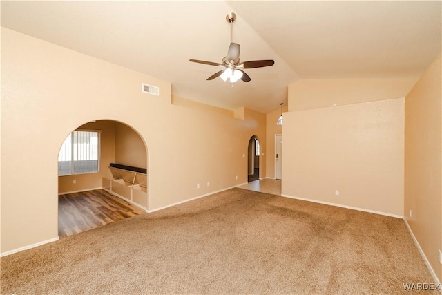 empty room with visible vents, baseboards, ceiling fan, carpet flooring, and arched walkways