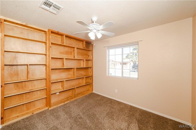 unfurnished room with visible vents, a textured ceiling, carpet floors, baseboards, and ceiling fan