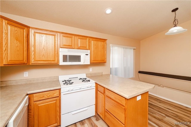 kitchen featuring light wood-type flooring, decorative light fixtures, white appliances, a peninsula, and light countertops