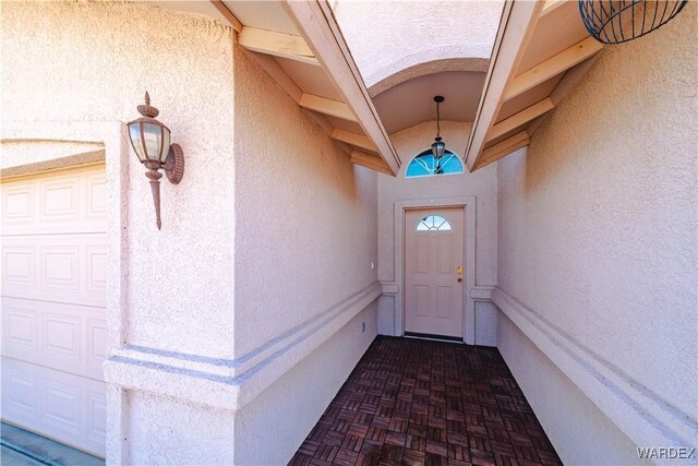 view of exterior entry with stucco siding and a garage