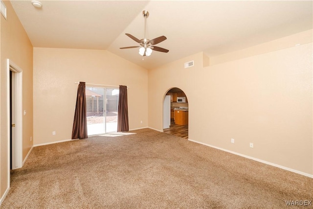 carpeted empty room with visible vents, baseboards, lofted ceiling, arched walkways, and a ceiling fan