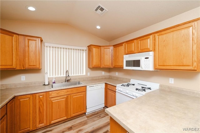 kitchen with visible vents, light countertops, lofted ceiling, white appliances, and a sink