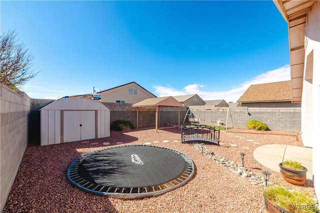 view of yard with a fenced backyard, a storage shed, a trampoline, and an outdoor structure