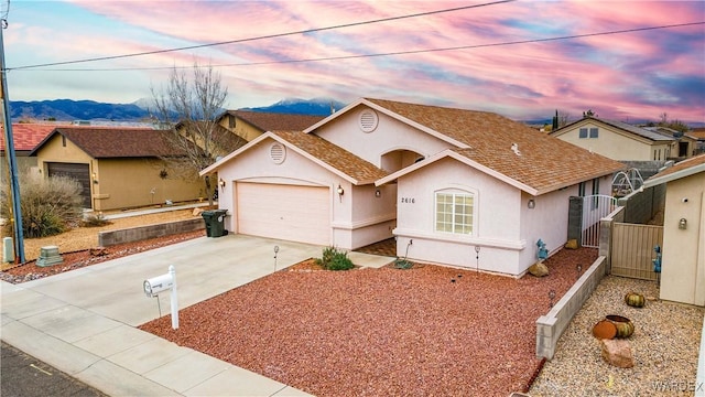 view of front of house featuring stucco siding, driveway, an attached garage, and a gate