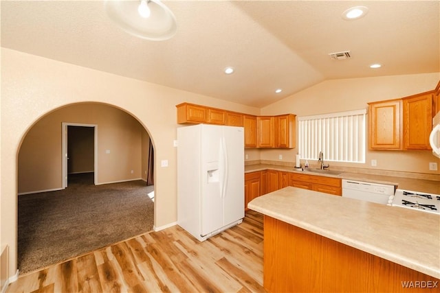 kitchen with visible vents, a sink, white appliances, arched walkways, and lofted ceiling