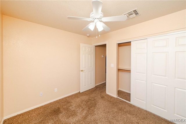 unfurnished bedroom featuring baseboards, visible vents, carpet floors, ceiling fan, and a closet