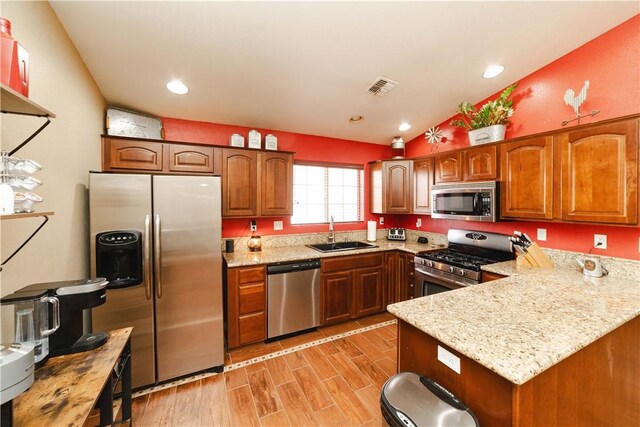 3048 Mallory Loop, Kingman, AZ 86401 - kitchen featuring stainless steel appliances, a sink, lofted ceiling, light stone counters, and a peninsula
