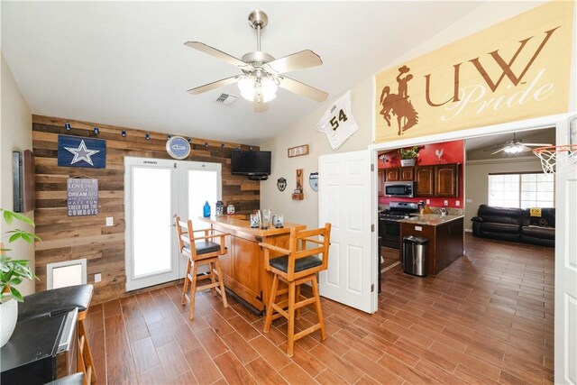 3048 Mallory Loop, Kingman, AZ 86401 - kitchen featuring stainless steel appliances, a ceiling fan, wood walls, lofted ceiling, and wood finished floors