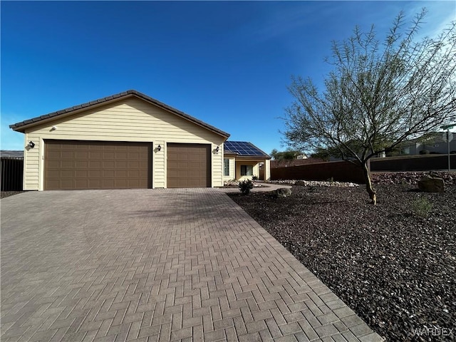 view of front of house with a tiled roof, decorative driveway, an attached garage, and roof mounted solar panels