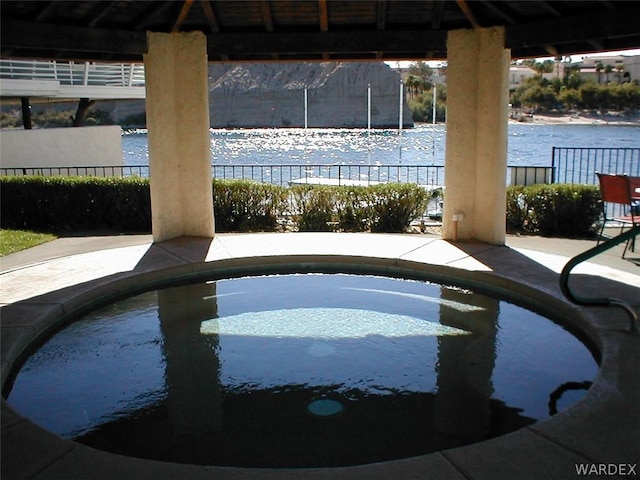 view of swimming pool with a water view and fence