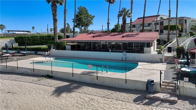 community pool with a patio area and fence