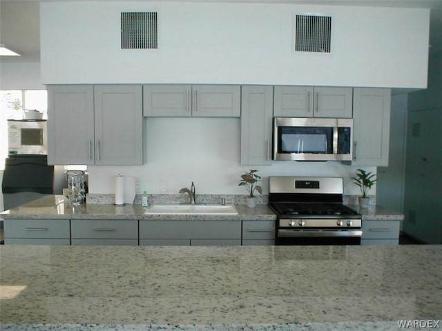 kitchen with stainless steel appliances, gray cabinets, a sink, and visible vents