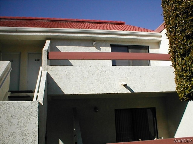 view of side of property featuring a tile roof and stucco siding