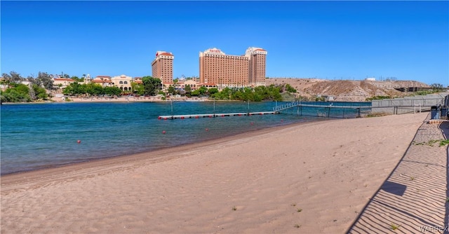 view of water feature featuring a view of city, fence, and a beach view