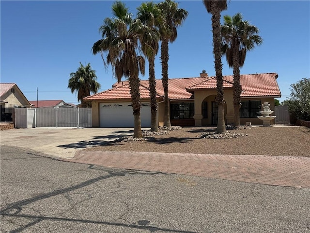 2024 E Mountain View Pl, Fort Mohave, AZ 86426 - mediterranean / spanish-style home with concrete driveway, a chimney, a tiled roof, stucco siding, and an attached garage