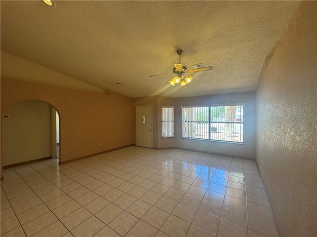 2024 E Mountain View Pl, Fort Mohave, AZ 86426 - empty room with a ceiling fan, light tile patterned floors, vaulted ceiling, arched walkways, and a textured ceiling