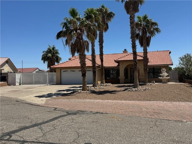 2024 E Mountain View Pl, Fort Mohave, AZ 86426 - mediterranean / spanish house with concrete driveway, stucco siding, a tile roof, a chimney, and a garage