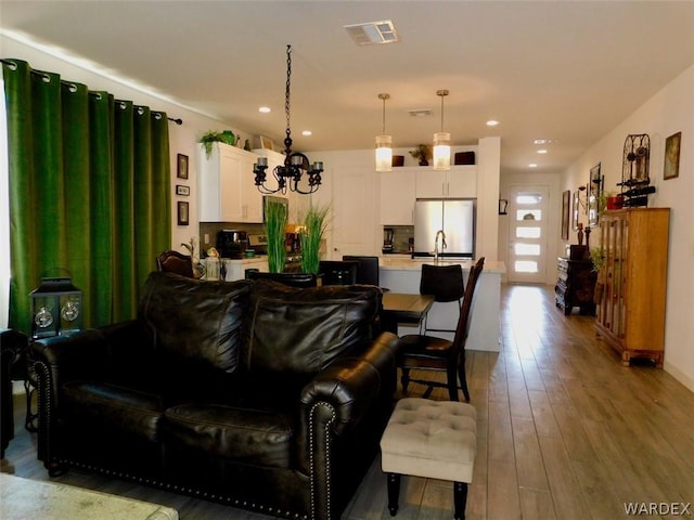 living room featuring an inviting chandelier, recessed lighting, visible vents, and light wood-style floors