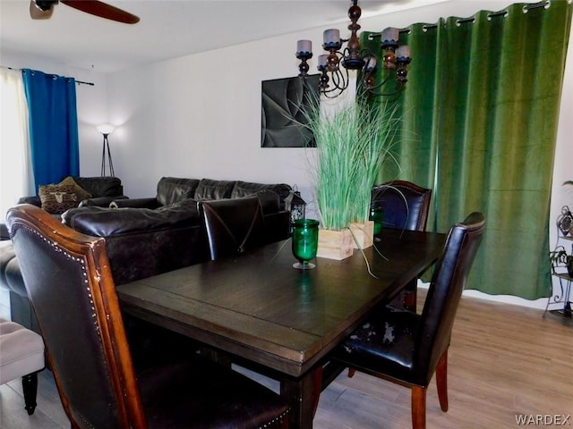 dining room with wood finished floors and ceiling fan with notable chandelier