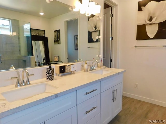 full bathroom with a stall shower, baseboards, a sink, and wood finished floors