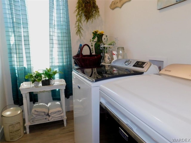 clothes washing area featuring washing machine and dryer, laundry area, and light wood-style flooring