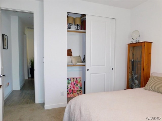 bedroom with baseboards, a closet, and light colored carpet