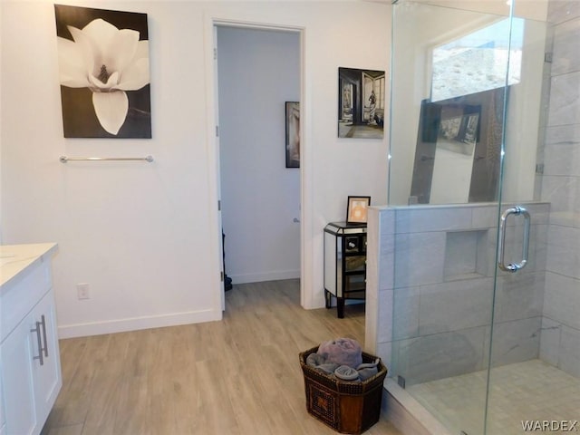 bathroom with a stall shower, baseboards, wood finished floors, and vanity