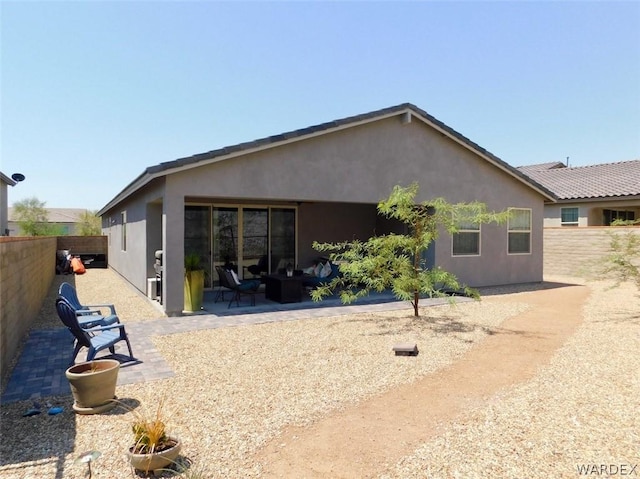 rear view of property featuring a patio area, fence, and stucco siding