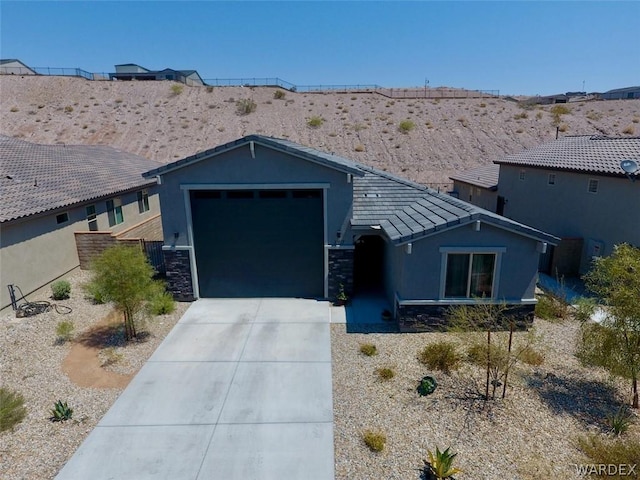 view of front of house featuring an attached garage, stone siding, concrete driveway, and stucco siding