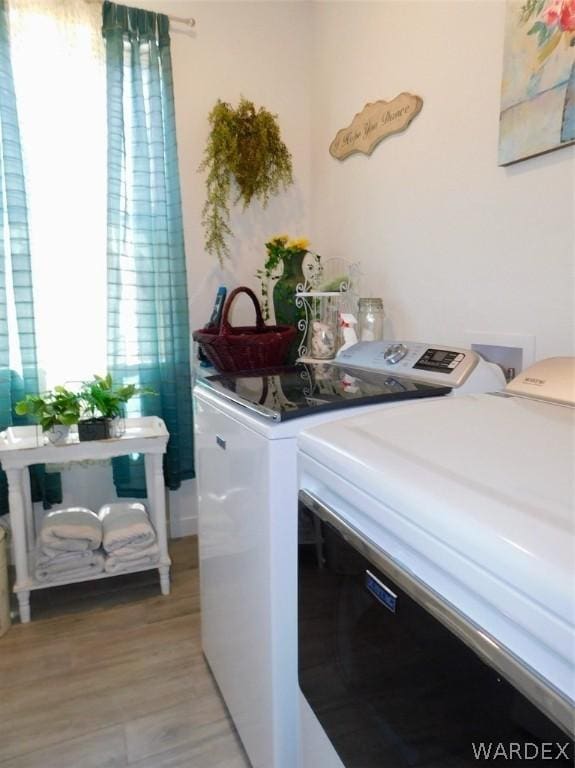 washroom with light wood-type flooring, washing machine and dryer, and laundry area