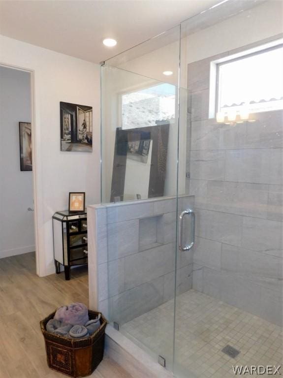 bathroom with baseboards, plenty of natural light, wood finished floors, and a shower stall