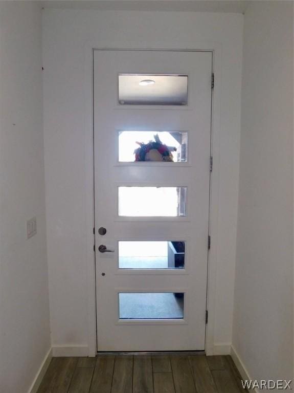 doorway with plenty of natural light, wood tiled floor, and baseboards