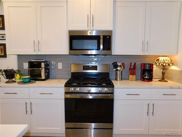 kitchen featuring tasteful backsplash, white cabinetry, and stainless steel appliances