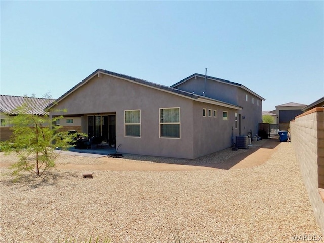 rear view of house with central air condition unit, fence, and stucco siding