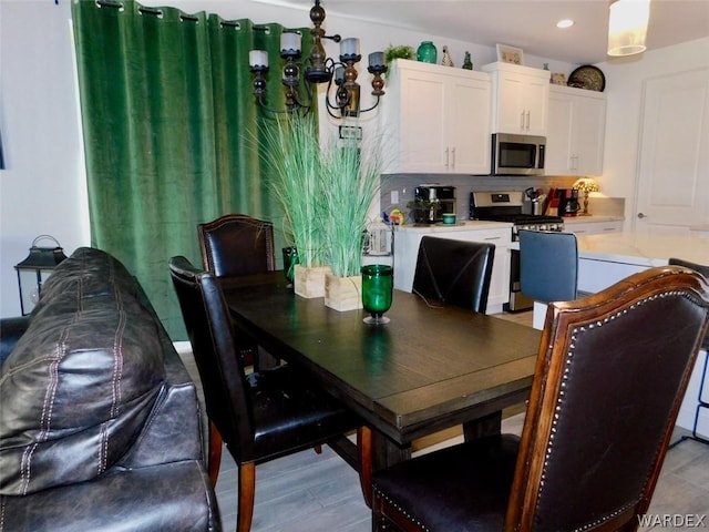 dining area with light wood finished floors, recessed lighting, and a notable chandelier