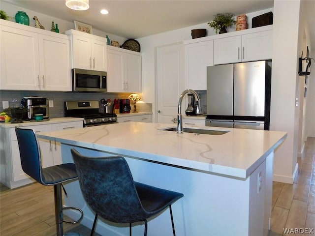 kitchen with a center island with sink, stainless steel appliances, and a sink