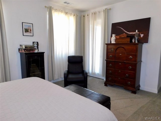 bedroom featuring baseboards, visible vents, and light colored carpet