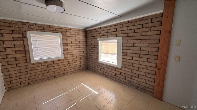 empty room featuring light tile patterned floors and brick wall